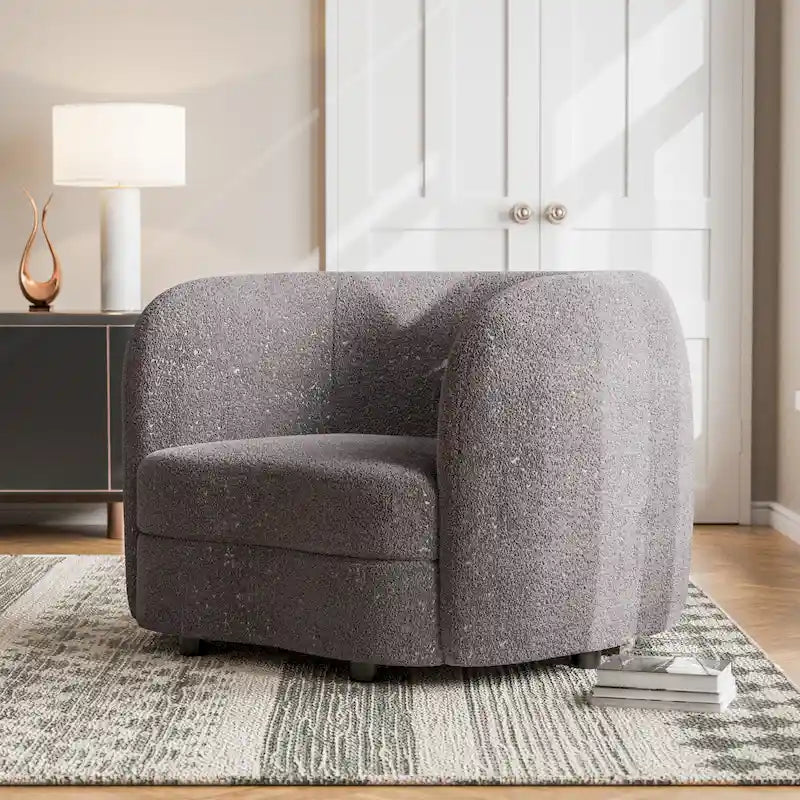 Fauteuil de style moderne doté d'accoudoirs incurvés, d'un coussin d'assise en forme de haricot et de pieds ronds en bois, recouvert d'un tissu bouclé.