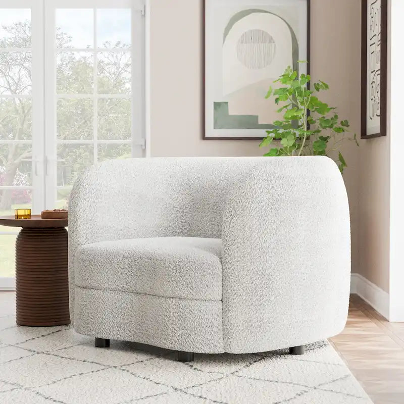 Fauteuil de style moderne doté d'accoudoirs incurvés, d'un coussin d'assise en forme de haricot et de pieds ronds en bois, recouvert d'un tissu bouclé.