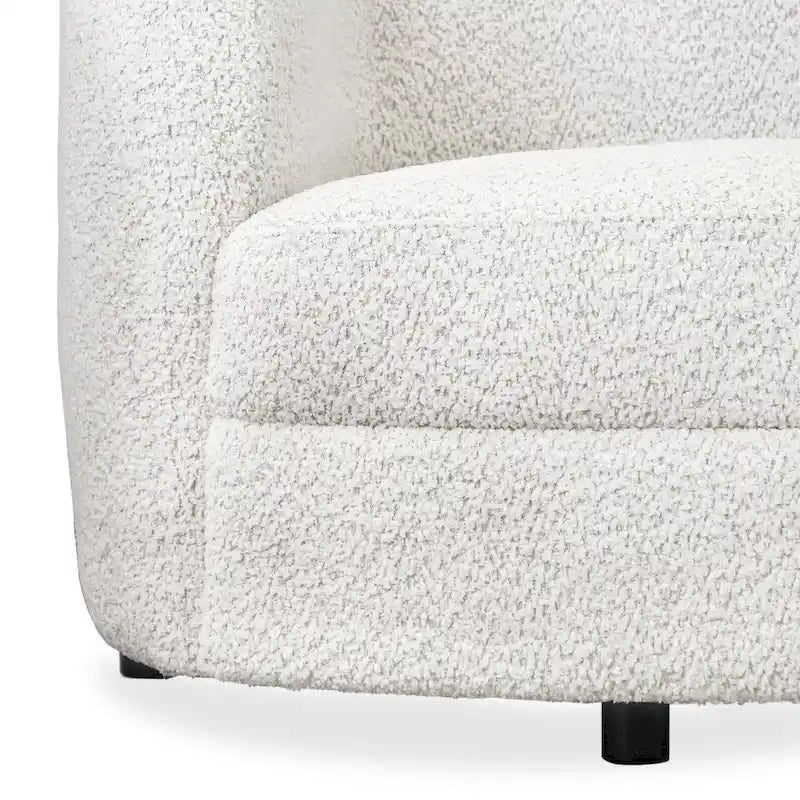 Fauteuil de style moderne doté d'accoudoirs incurvés, d'un coussin d'assise en forme de haricot et de pieds ronds en bois, recouvert d'un tissu bouclé.