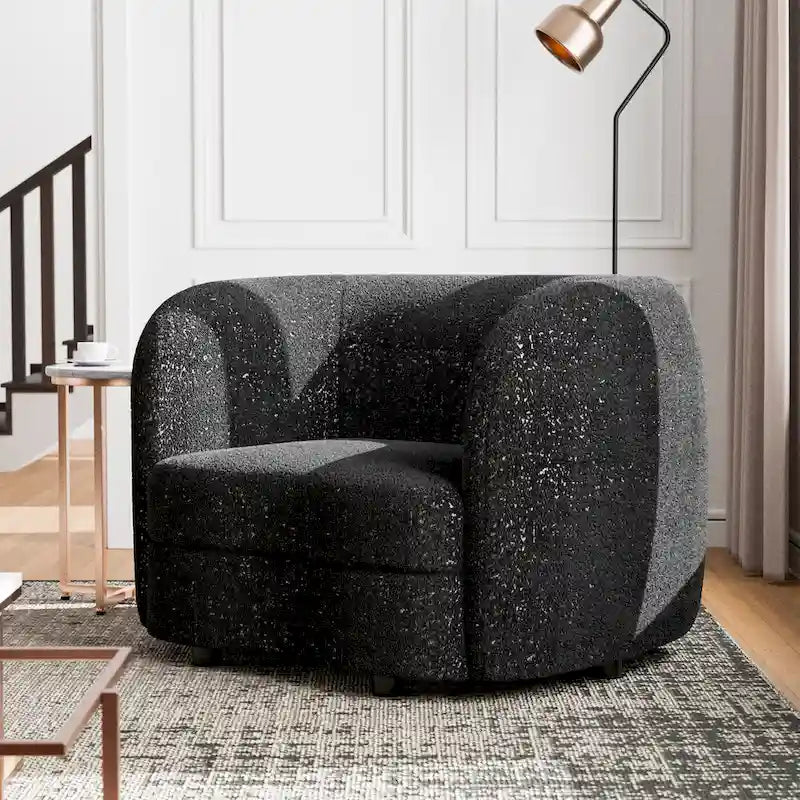 Fauteuil de style moderne doté d'accoudoirs incurvés, d'un coussin d'assise en forme de haricot et de pieds ronds en bois, recouvert d'un tissu bouclé.