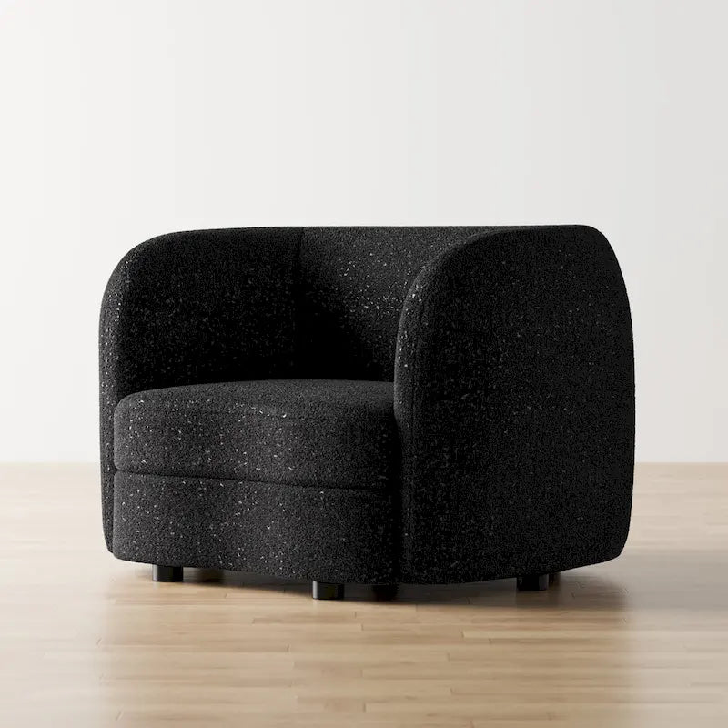 Fauteuil de style moderne doté d'accoudoirs incurvés, d'un coussin d'assise en forme de haricot et de pieds ronds en bois, recouvert d'un tissu bouclé.