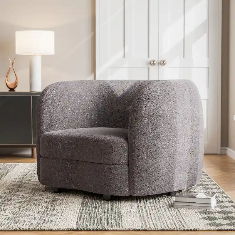 Fauteuil de style moderne doté d'accoudoirs incurvés, d'un coussin d'assise en forme de haricot et de pieds ronds en bois, recouvert d'un tissu bouclé.
