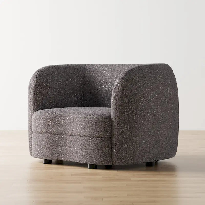 Fauteuil de style moderne doté d'accoudoirs incurvés, d'un coussin d'assise en forme de haricot et de pieds ronds en bois, recouvert d'un tissu bouclé.