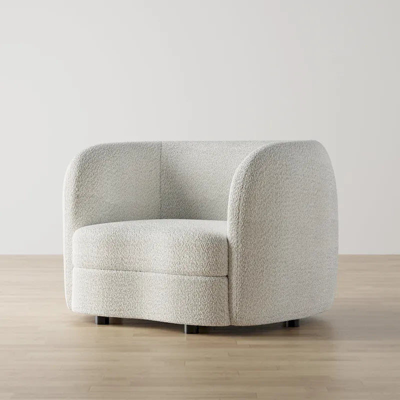 Fauteuil de style moderne doté d'accoudoirs incurvés, d'un coussin d'assise en forme de haricot et de pieds ronds en bois, recouvert d'un tissu bouclé.